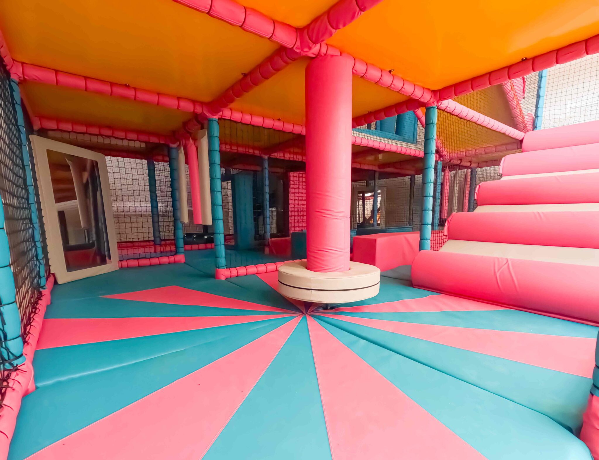 Pink and white dizzy disc with blue and pink applique floorboards found at Rushall School's indoor softplay area designed by Play Creations