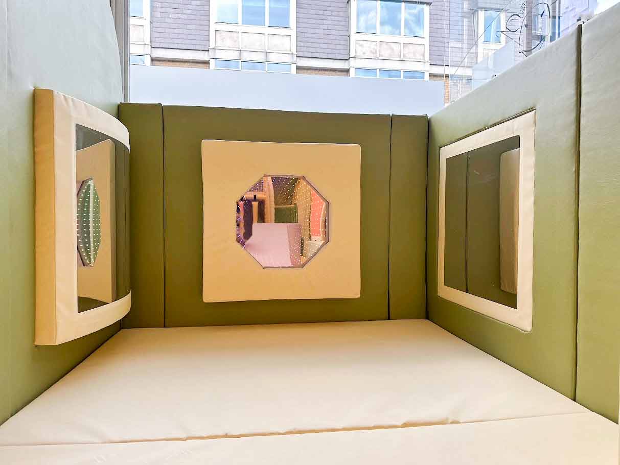 Three sensory wall panels on green walls. There's an LED inifity mirror and a wobble mirror and a mirror panel.