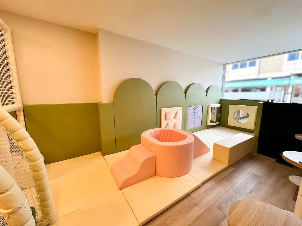Overheard shot of Moo Moo's play cafe. The play area is pink, cream and green and features a soft play toy pit in the middle.