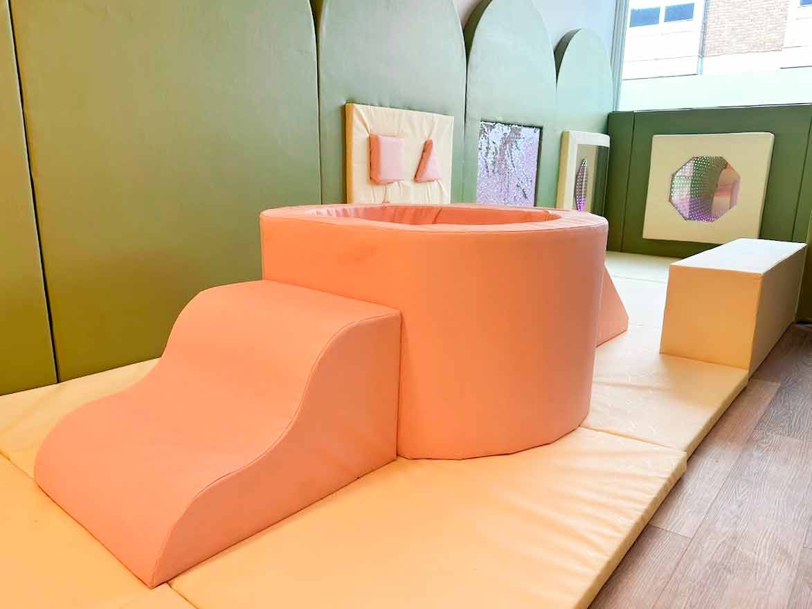 pink soft play toy pit with a soft play ramp and stairs leading up to it. Found at Moo Moo's play cafe.