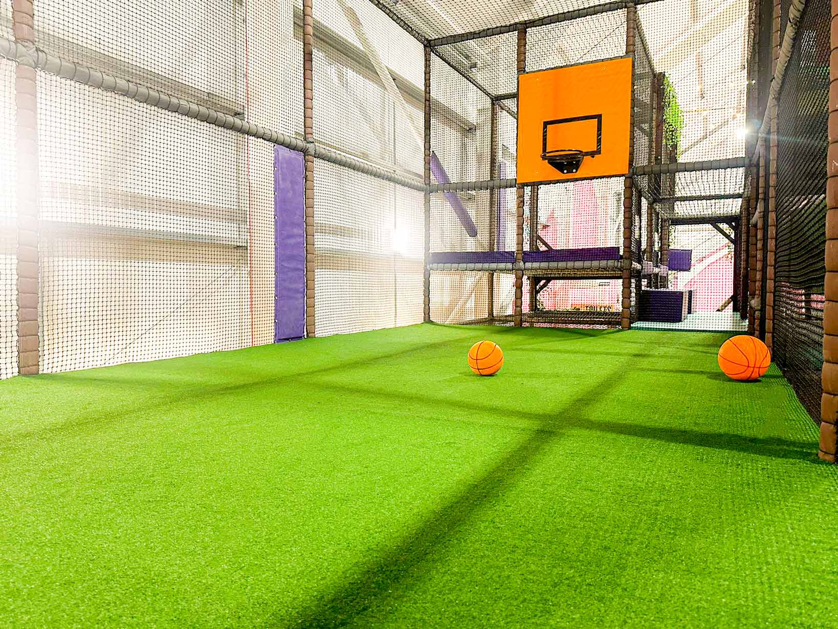 Brocksbushes' Indoor Softplay custom sports area. The astro turf is green with two orange basket balls. This was designed by Play Creations.