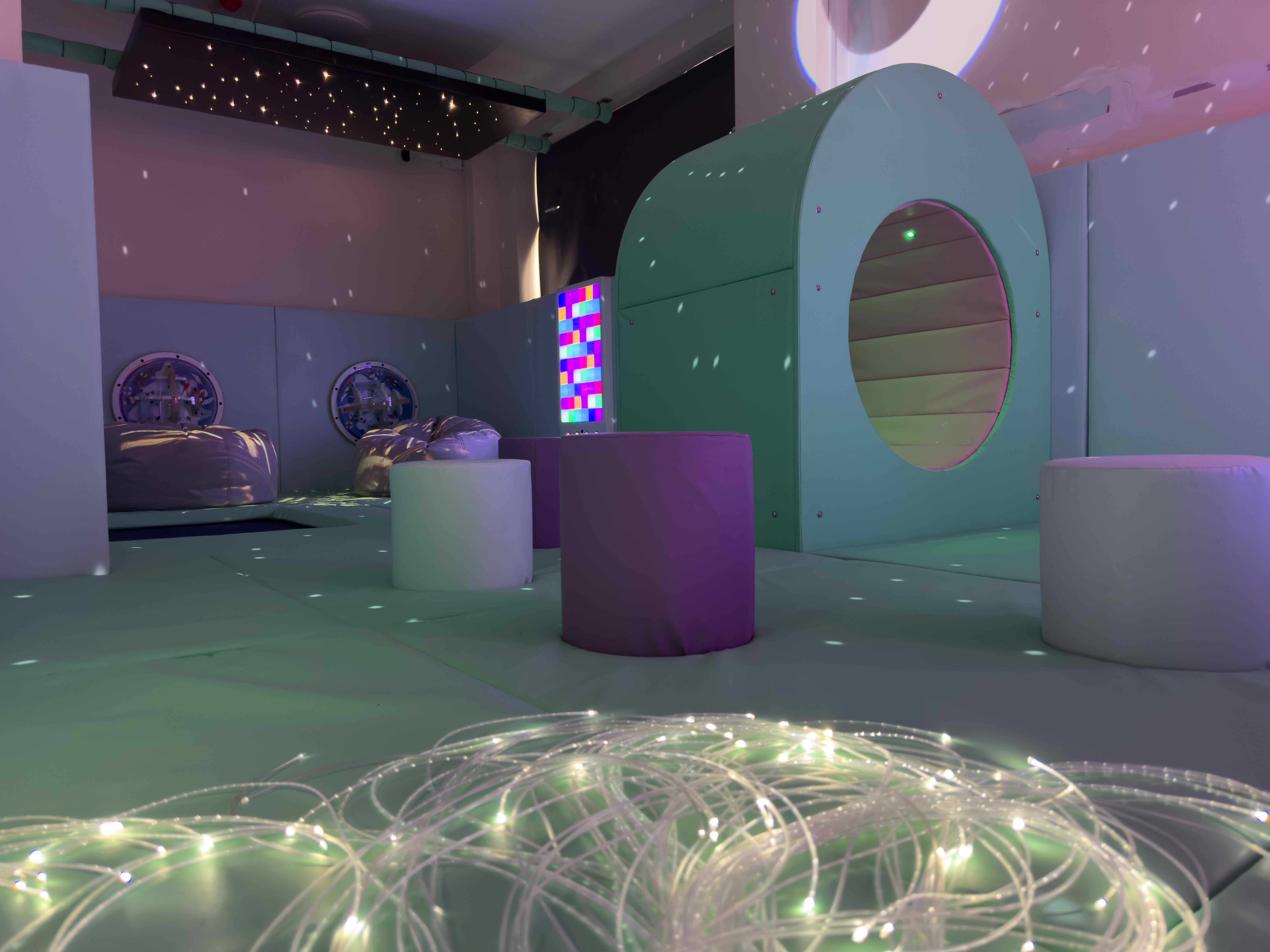 Our Special Angels Sensory room. Featuring a calming blue theme. There are 2 purple bean bags, a blue sensory nook, and fibre optic strands.