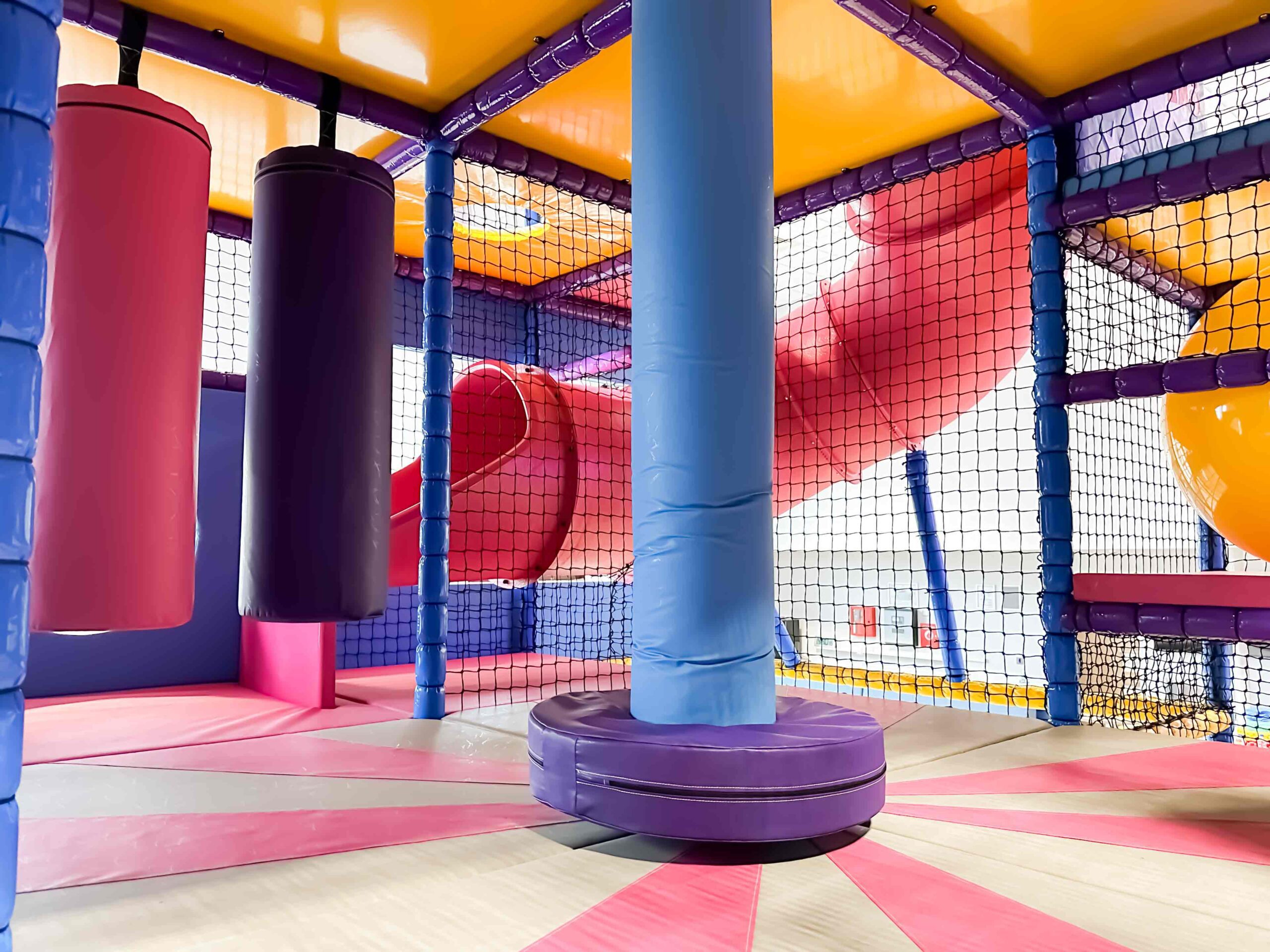 Blue and purple dizzy disc with white and pink applique floorboards at RAF Lakenheath's indoor softplay area designed by Play Creations