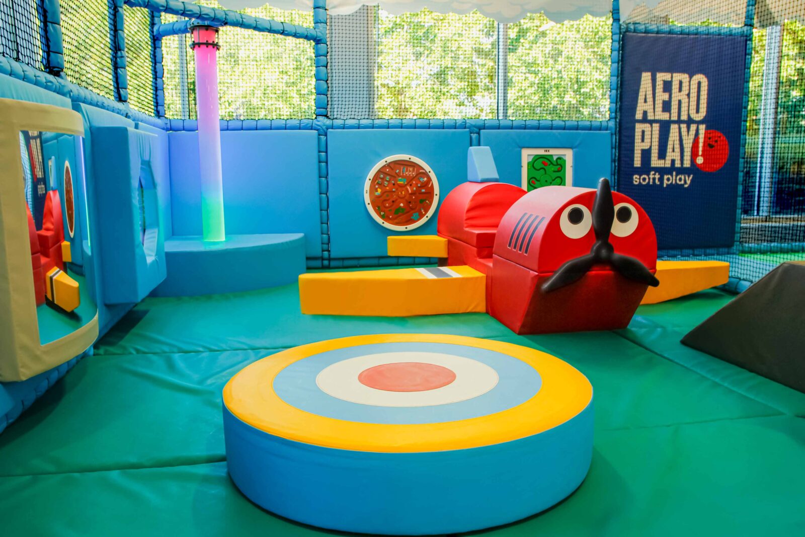 Toddler area at the RAF Museum's indoor softplay area. Featuring a small softplay plane for children to climb on, a spinner and LED light tube. Everything fits a yellow, red and blue theme.