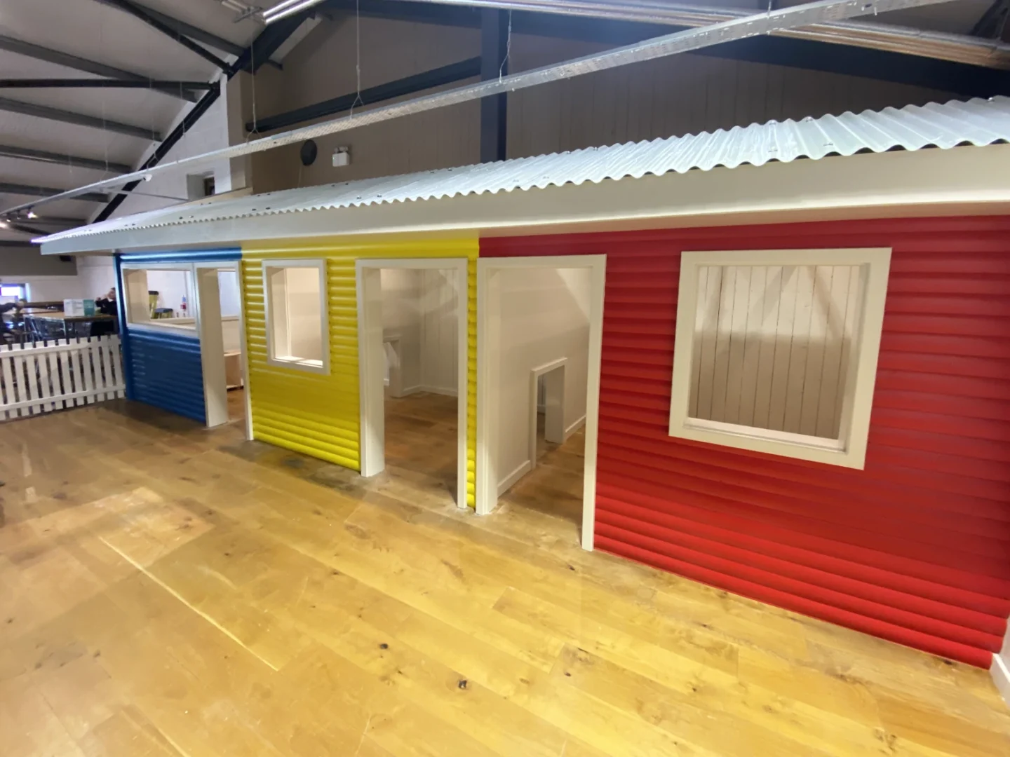 Red, yellow and blue themed houses built for roleplay areas to go inside them. They have a white crinkled roof running across all three.