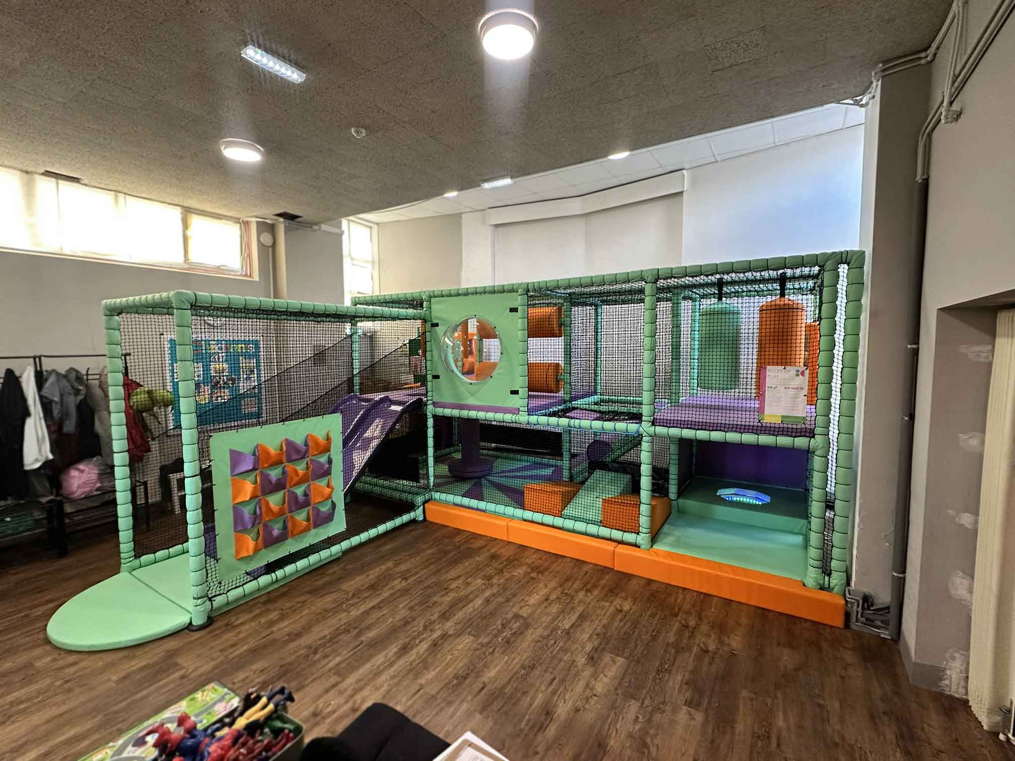 Temple Park Centre's indoor softplay installation featuring a blue, orange and purple themed colour scheme matching their brand colours. There is a slide, custom shoe rack and more featured in the softplay designed by Play Creations