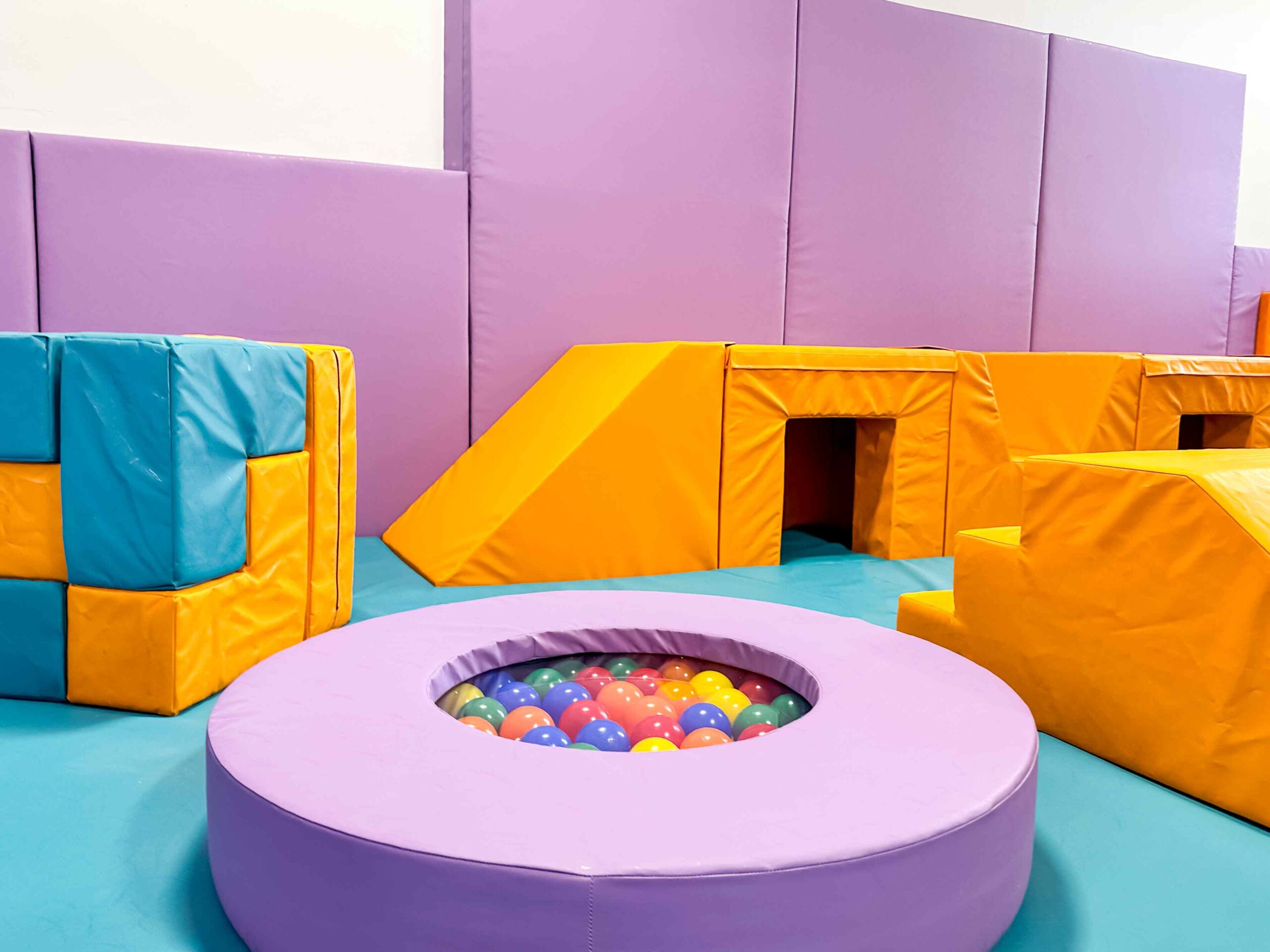 Purple Spinning Ball Pit next to a Blue and Orange SOMA Cube at Craigentinny's indoor softplay area designed by Play Creations.