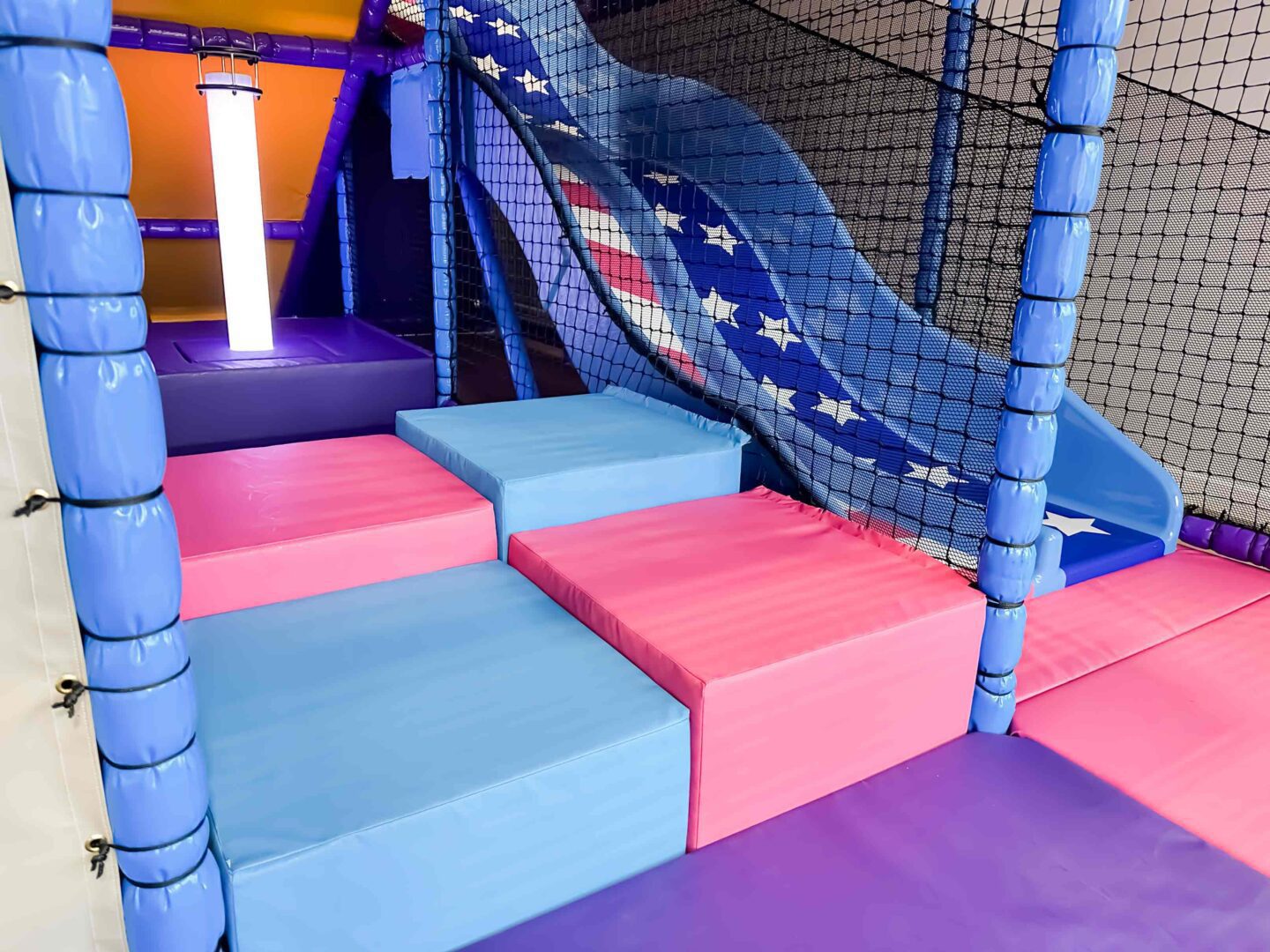 Pink and Blue Cubed floor leading to LED Light Tube next to the twin lane slides at RAF Lakenheath's indoor softplay area designed by Play Creations