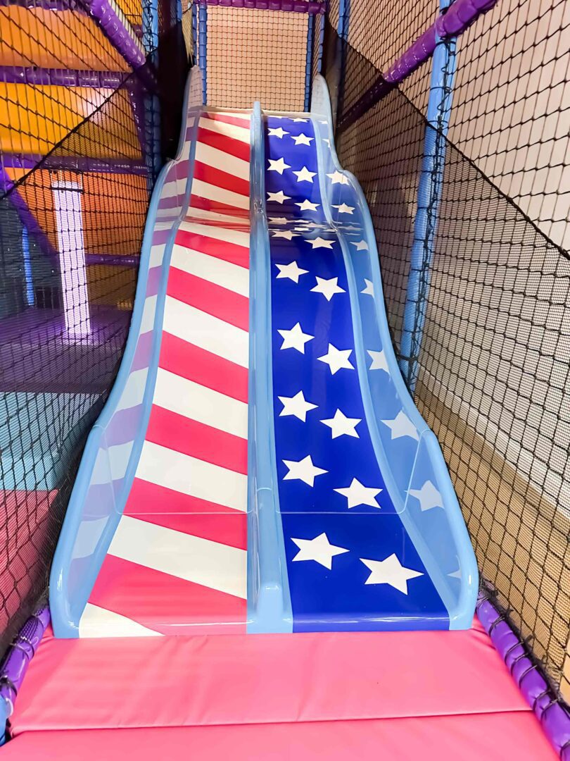 Red, white and blue stripes and stars twin lane slide found at RAF Lakenheath's indoor softplay centre, designed by Play Creations.