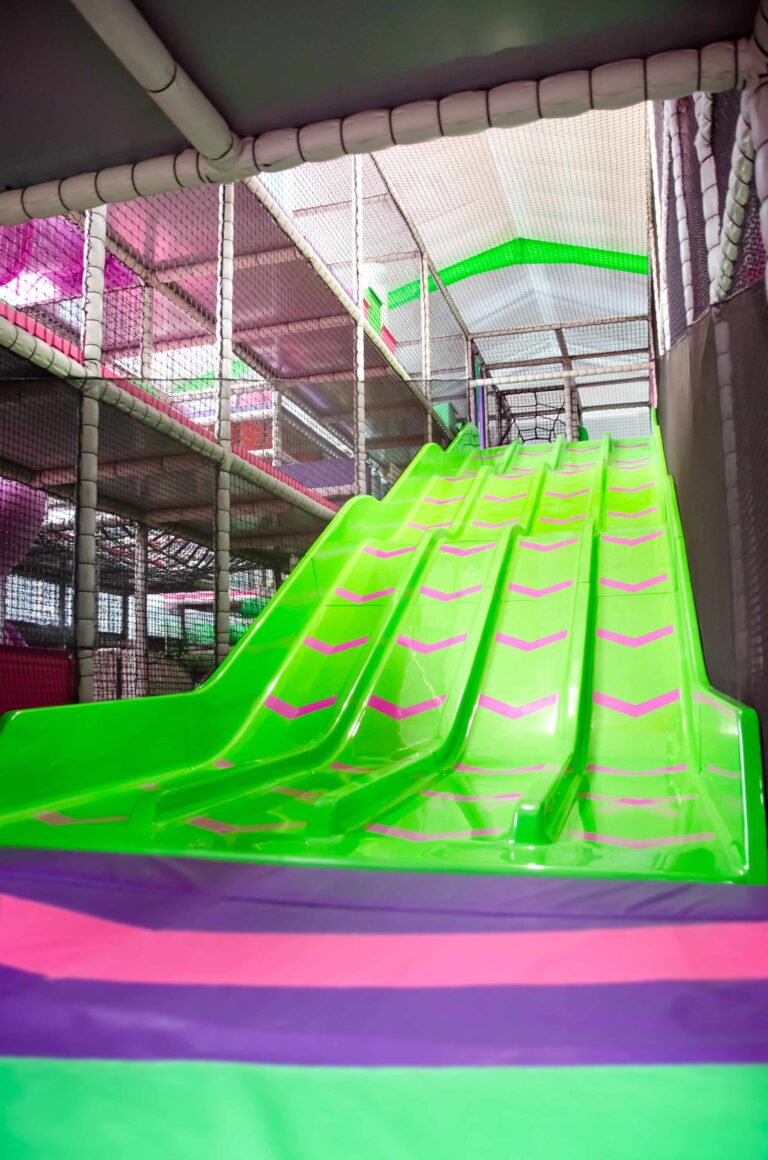 This is the 4 Laned Astra Slide at Fun Factory's indoor softplay. The slide is green with pink arrows. The slide is wavy and goes up 3 levels.