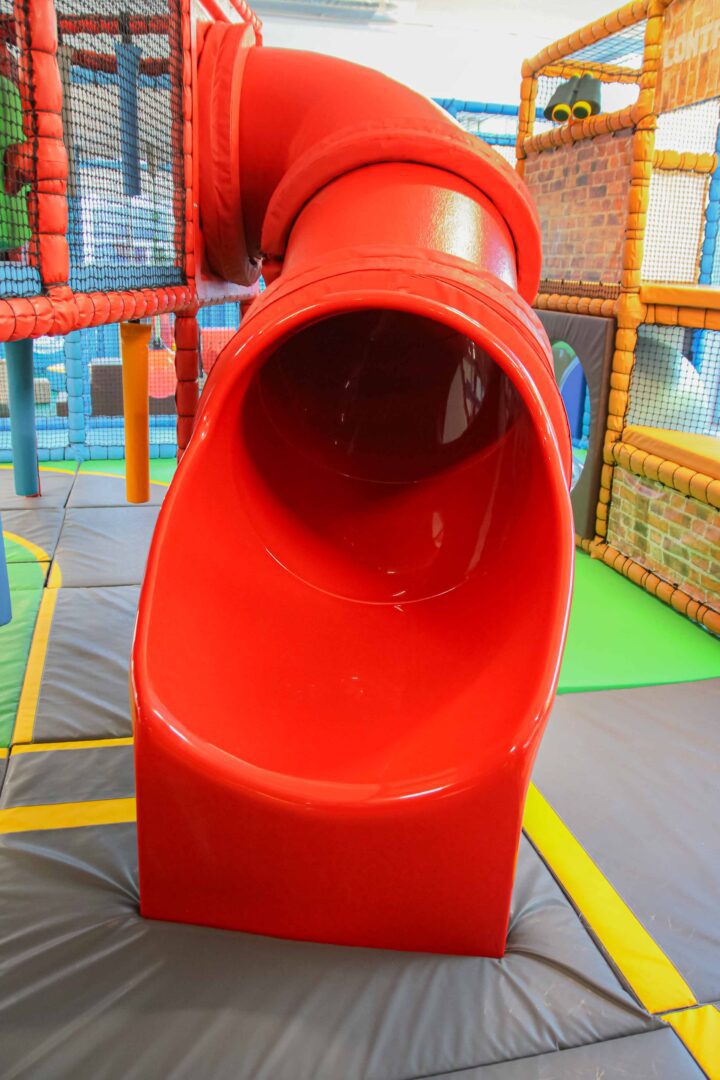 A red tube slide found at the RAF Museum's indoor play area, designed by Play Creations.