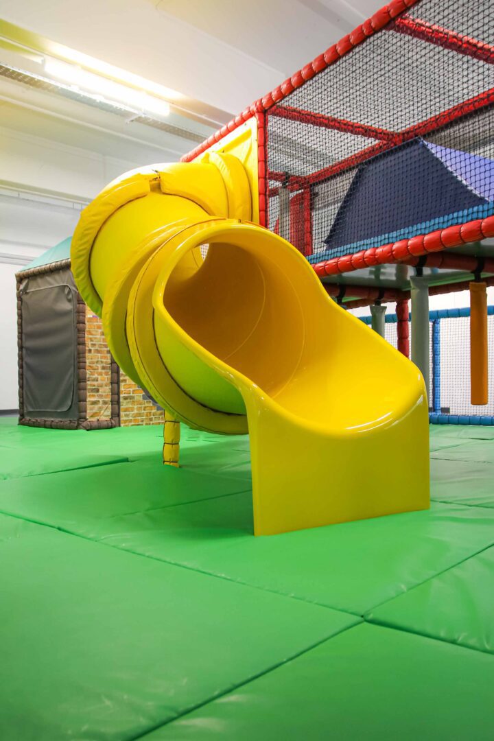 A yellow tube slide found at the RAF Museum's indoor play area, designed by Play Creations.