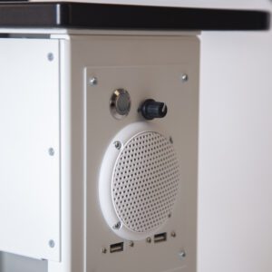Closeup of the control panel and speaker on Playhubs entertainment console. Showcases a circle speaker and a dial, along with two usb ports.