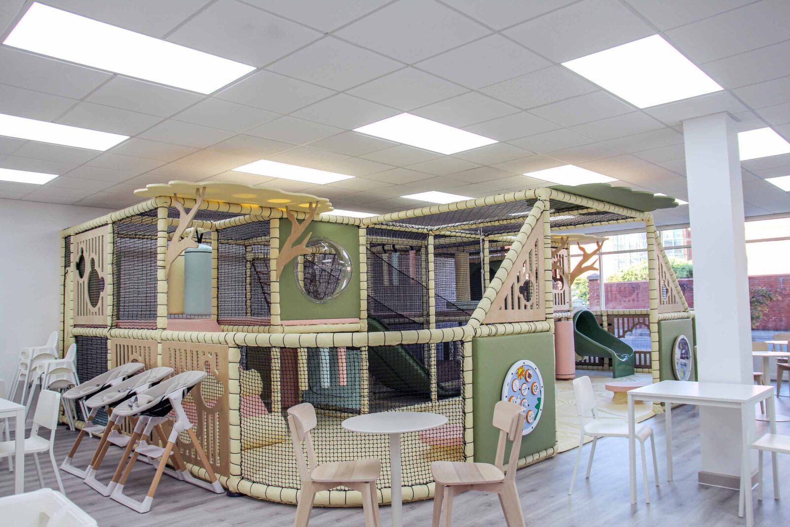 Cub and Cup Softplay Cafe in Swindon. The color scheme is cream, green, pink and blue which complement the cozy atmosphere. There are bear wooden features that are on the side of the softplay. Alongside bespoke tree panels to add to the aesthetics.